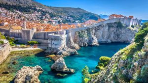 Aerial shot of Dubrovnik in Croatia with bright blue color of Adriatic sea beside a steep cliffside 